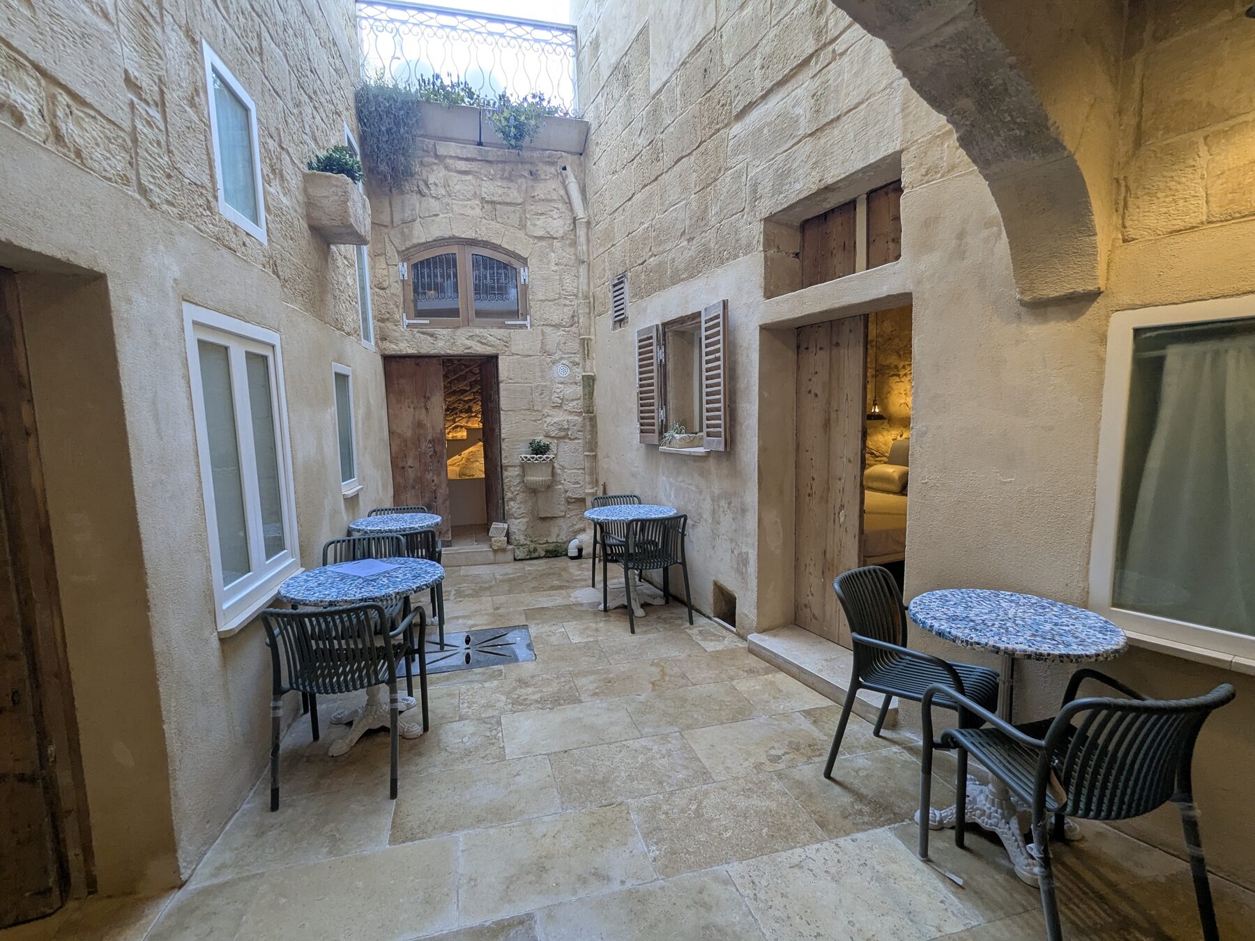 Inner courtyard with mosaic café tables and Maltese stone walls